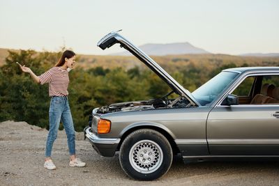 Side view of woman standing in car