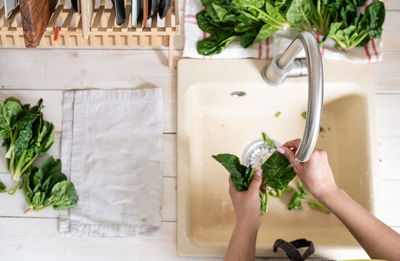 Healthy eating and dieting. young smiling woman in home clothes washing spinash in the kitchen