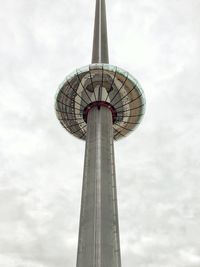 Low angle view of communications tower against cloudy sky