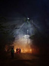 Illuminated street lights on road against sky at night