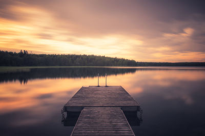 Pier on lake against sky during sunset