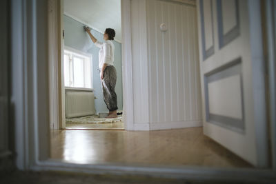 Woman painting wall at home