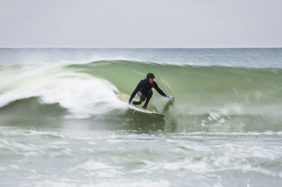 Motion blur of man surfing winter wave