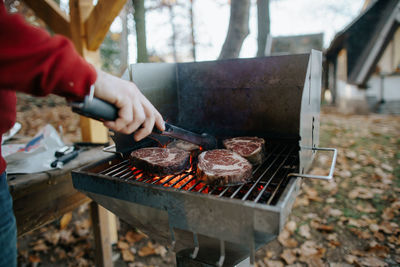 Cropped image of man preparing food on barbecue grill in yard
