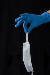 Close-up of hand holding umbrella over black background