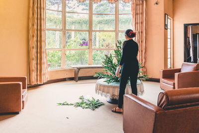 Woman standing by potted plants at home