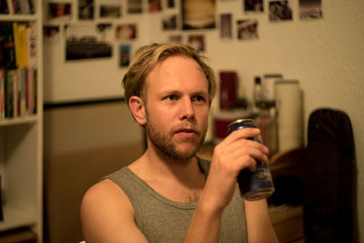 Thoughtful mid adult man with beer can looking away at home