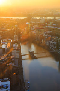 High angle view of river by buildings in city during sunset