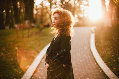 Side view of woman standing by tree in forest