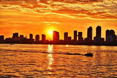 Sea and cityscape against sky during sunset