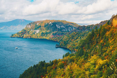 Scenic view of sea by mountains against sky