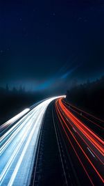 Light trails on road against sky at night