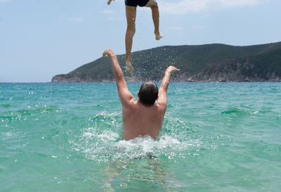 Rear view of shirtless boy in sea