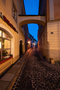 Empty footpath amidst buildings in city at night