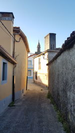 Footpath amidst buildings in town against sky