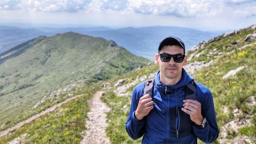 Portrait of man wearing sunglasses while standing against mountains