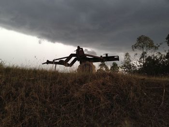 View of field against cloudy sky