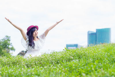 Woman with arms outstretched on grass