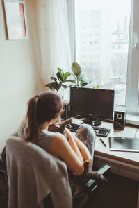 Woman using mobile phone while sitting on table at home