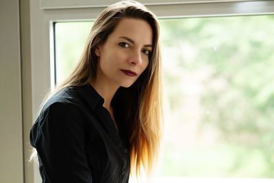 Portrait of beautiful mid adult woman by window at home