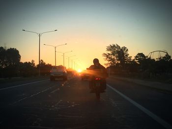 Silhouette of vehicles on road at sunset