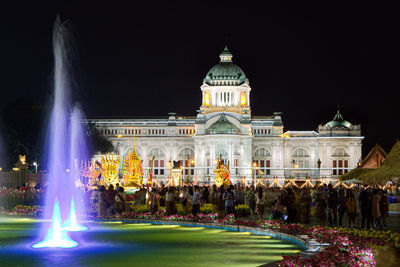 Illuminated fountain in city against sky at night