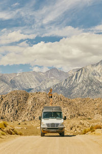 Young woman on roof of camper van on road in northern california.