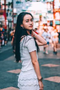 Portrait of young woman standing on street at night