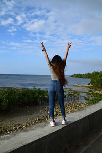 Rear view of woman standing in sea against sky