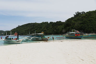 Boats moored on beach against sky