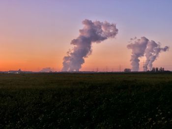Smoke emitting from chimney on field against sky