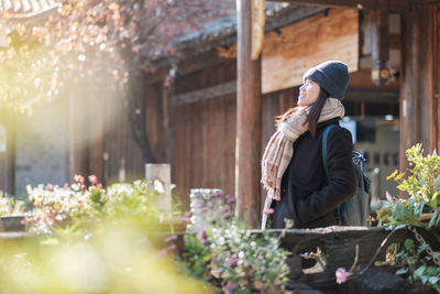 Rear view of woman standing by flowering plants during winter