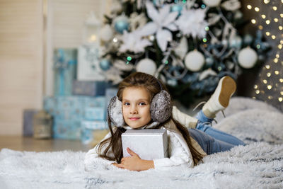 Portrait of smiling young woman sitting on christmas tree