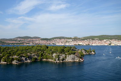 Scenic view of sea by townscape against sky