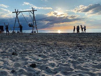 People on beach against sky during sunset