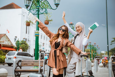 Young woman with arms raised standing in city