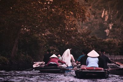 Rear view of people sitting on boat in river