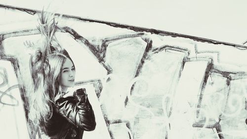 Young woman standing against sky