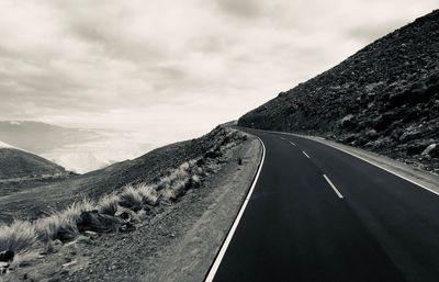 Diminishing perspective of mountain road against cloudy sky