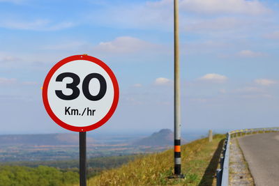 Information sign on road against sky