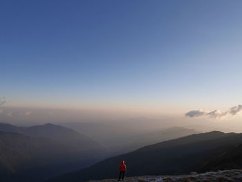 Person standing against mountains during sunset