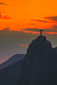 Silhouette mountain standing on rock against sky during sunset