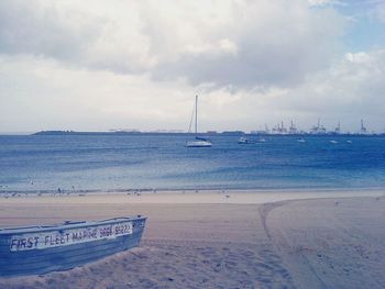 View of boats in calm sea against cloudy sky