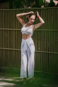 A young woman stands in a white suit on a green background