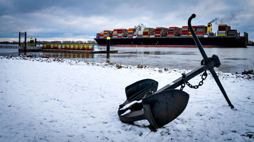 Boat moored on snow covered field against sky