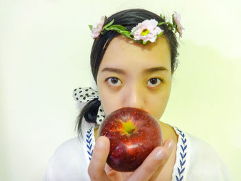 Portrait of girl holding apple against white background