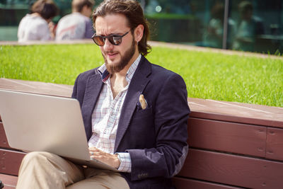Young man using laptop while sitting on bench