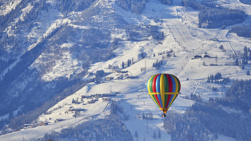 Hot air balloon flying over snow covered mountain