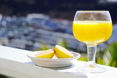 Close-up of fruit in plate by drink on retaining wall