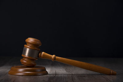 Close-up of padlock on wood against black background